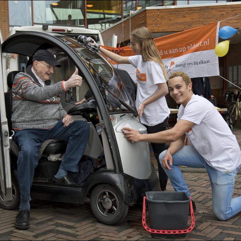 Vrijwilligers wassen een brommobiel